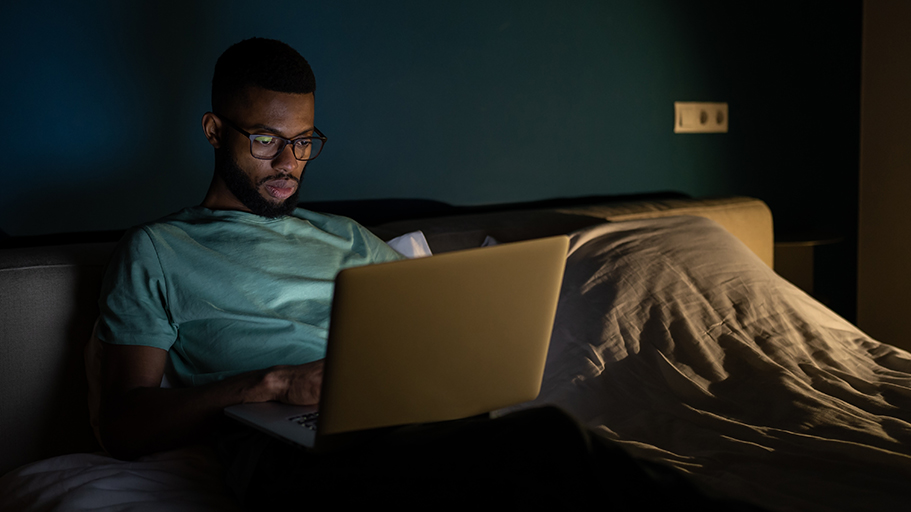 Man sitting in bed working on laptop